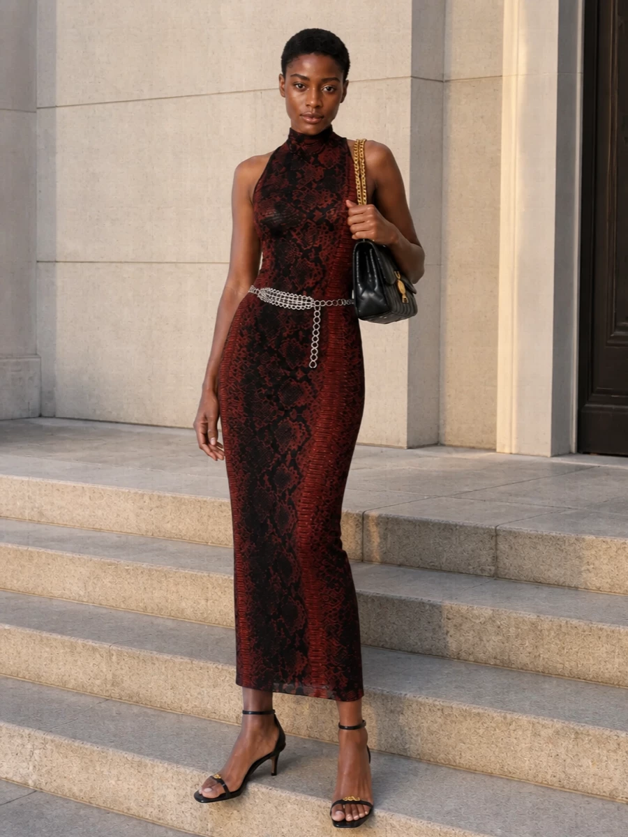 A slinky, serpentine halter dress anchors this night-out ensemble, its dark mahogany and black print setting a moody, after-hours tone. Barely there black stiletto sandals and a quilted black-and-gold shoulder bag keep the line clean and luxurious while echoing the dress’s attitude. A silver chain belt adds just enough hardware and y2k edge, sharpening the waist without disturbing the body-hugging silhouette.