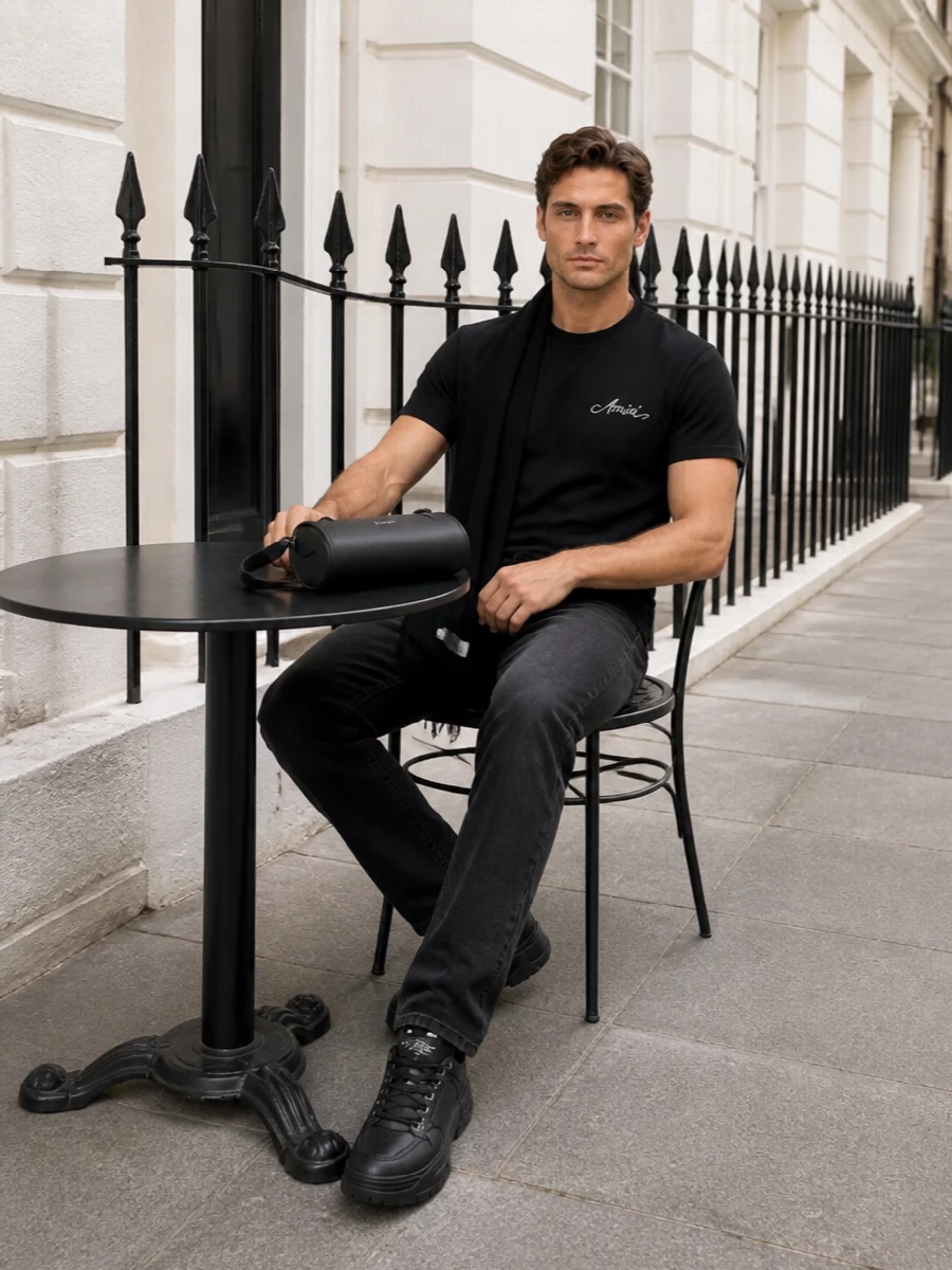 A black Amiri tee and washed-black straight denim create a clean, LA-informed uniform that feels deliberate without being loud. Chunky black sneakers keep the line grounded, while the sculpted McQueen crossbody and a dark scarf add just enough structure and texture to read as grown-up streetwear rather than casual basics.