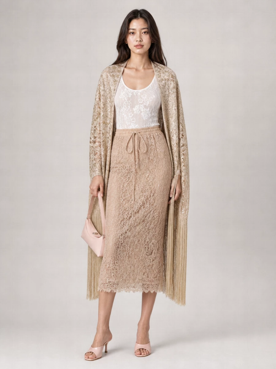 A tonal story of blush and ivory lets the lace skirt take center stage, with the fitted bodysuit creating a smooth, uninterrupted line. Blush satin heels and a matching baguette keep everything soft yet polished, while the fringed stole adds a hint of old-world glamour for cocktail hours and intimate dinners.