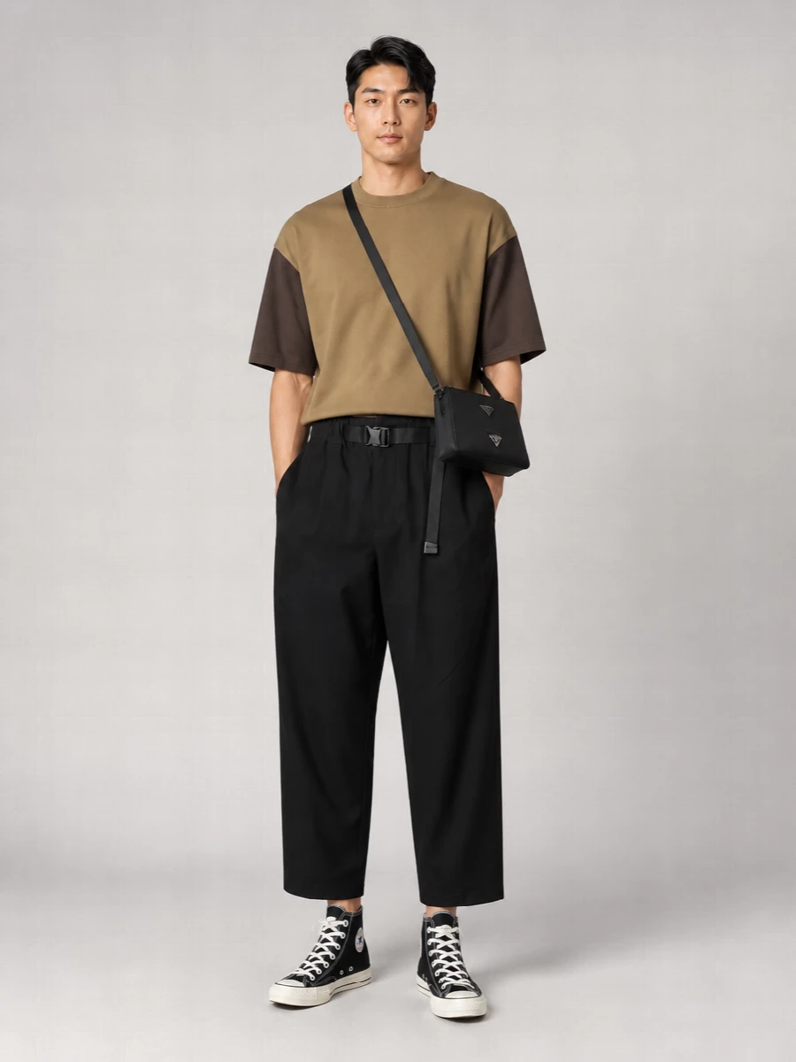 Camel and dark brown block into a clean boxy tee, dropped over cropped black trousers for an easy, graphic column of volume. Black hi‑tops and a structured crossbody keep the energy grounded in the city, while a slim belt adds just enough definition at the waist.