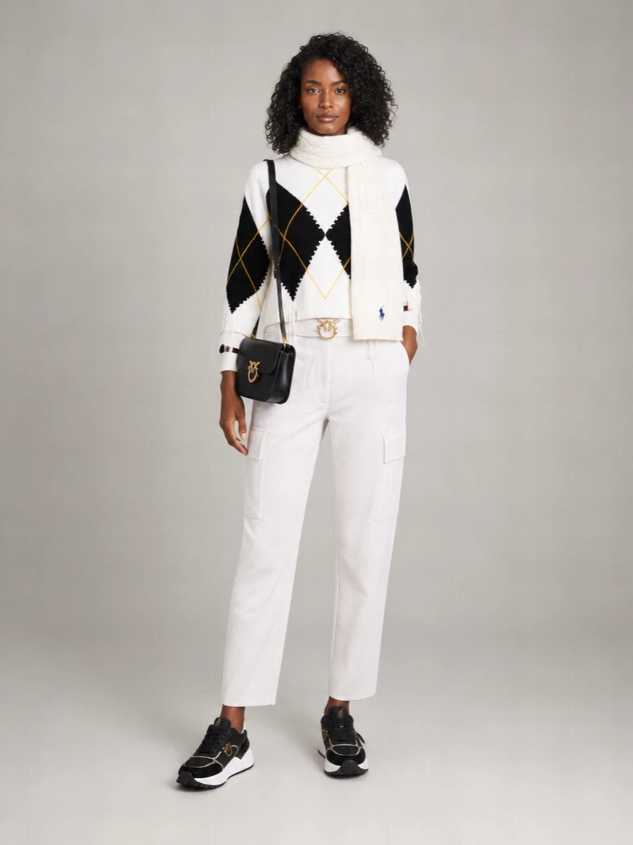 A graphic argyle knit meets crisp off white cargos for a city-ready take on preppy. Chunky monochrome sneakers and a structured black cross-body sharpen the attitude while keeping it easy for everyday. The result is relaxed but intentional, ideal for coffee runs that turn into all-day plans.