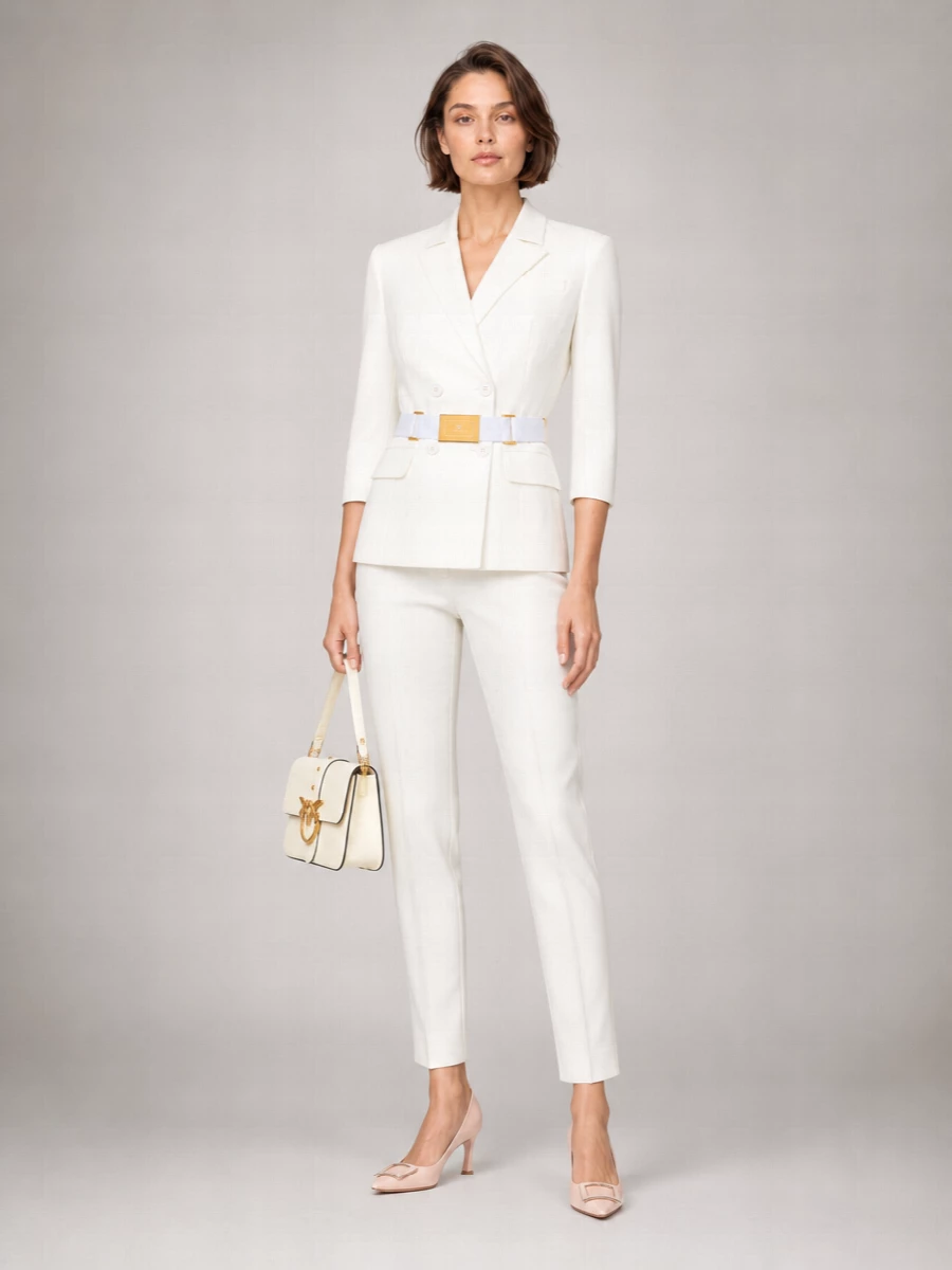 A sharp white blazer and softly pleated white trouser create a long, tailored line that feels composed yet light for warm weather. Blush pumps and a buttercream flap bag introduce a gentle whisper of color while staying in the same quiet luxury mood. Gold hardware threads through each piece so the outfit reads intentional from client lunch to late dinner reservations.
