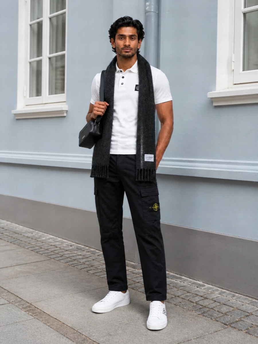 A crisp white Stone Island polo is grounded with black tapered cargos for a disciplined take on streetwear. Clean Prada low-tops keep everything sharp and graphic, while a compact Jacquemus bag and charcoal scarf add just enough texture and polish without breaking the monochrome story.
