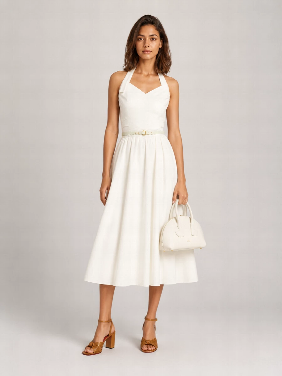 An ivory halter dress is paired with caramel block-heel sandals and a sculpted ivory mini top-handle for a quietly romantic summer occasion ensemble. A slim scalloped belt in soft pastels gently defines the waist, keeping the silhouette light, feminine and polished from terrace cocktails to garden parties.