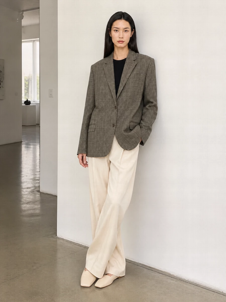 A softly structured checked blazer meets light beige wide-leg tailoring for a clean, elongated silhouette that feels precise but unfussy. Buttercream flats keep the mood calm and grounded, while a taupe crescent bag adds just enough sculptural detail without disturbing the minimalist palette. The result is quiet, modern tailoring that moves easily from daytime meetings to understated dinners.