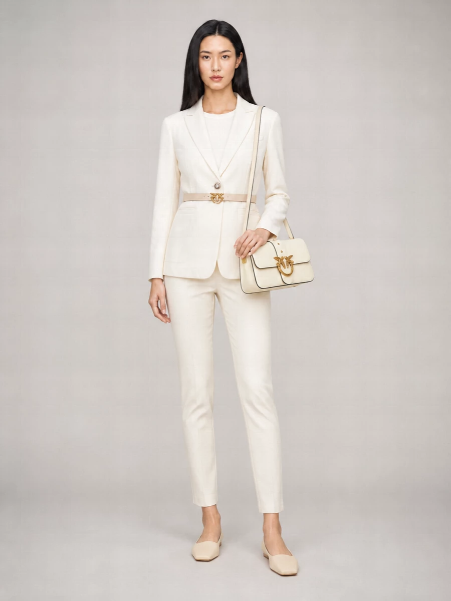 A softly tonal Pinko suit in ivory and buttercream keeps the line long and lean, letting clean tailoring do the work. Square-toe flats and a structured flap bag keep it modern and city-ready, while the slim nude belt quietly highlights the high waist for a precise, feminine finish.