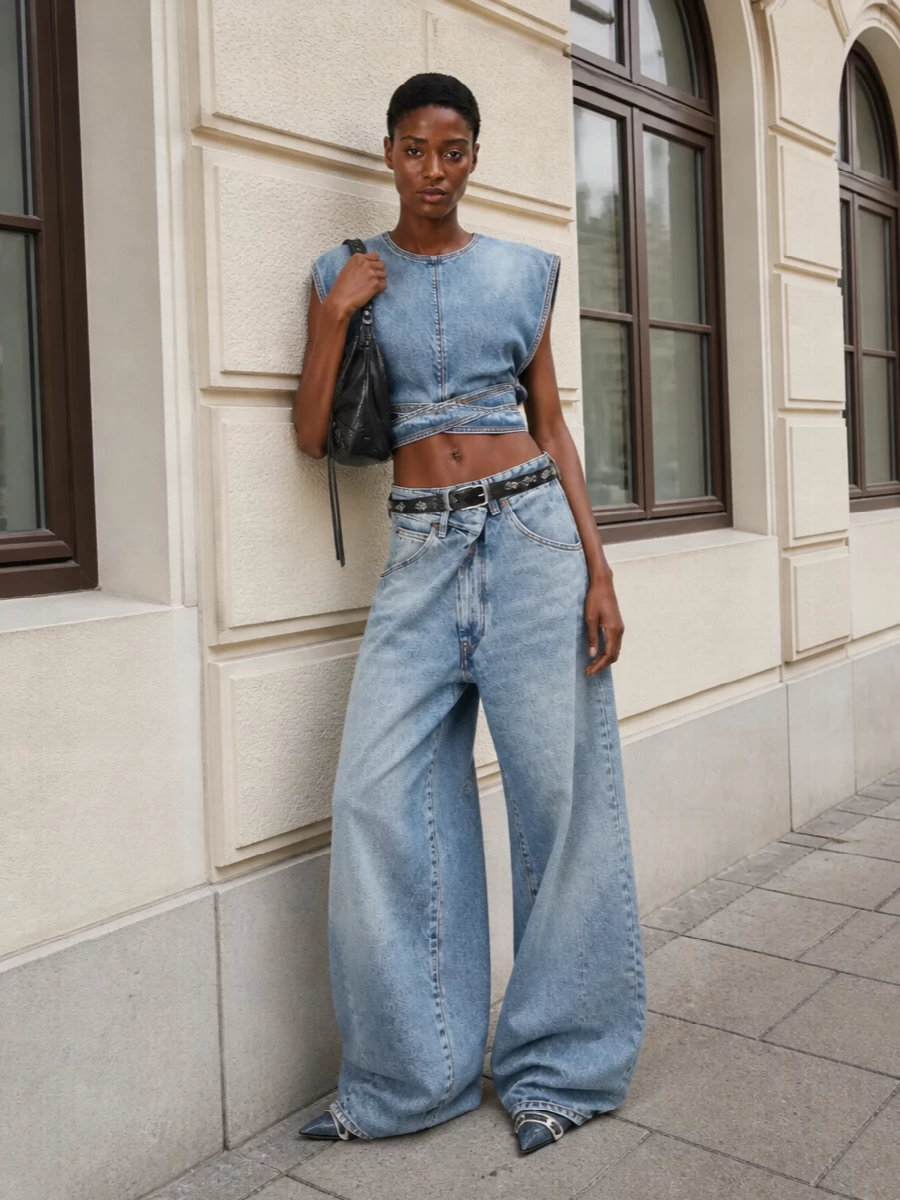 All-denim goes precision: the sculpted Alaïa crop snaps the waist against Darkpark’s exaggerated leg, while the Diesel knee boot hides under the puddled hem for a razor-clean line. A black bikered Balenciaga shoulder bag and slim Prada belt bring just enough hardware and contrast to keep the palette focused in blue but the mood firmly downtown.