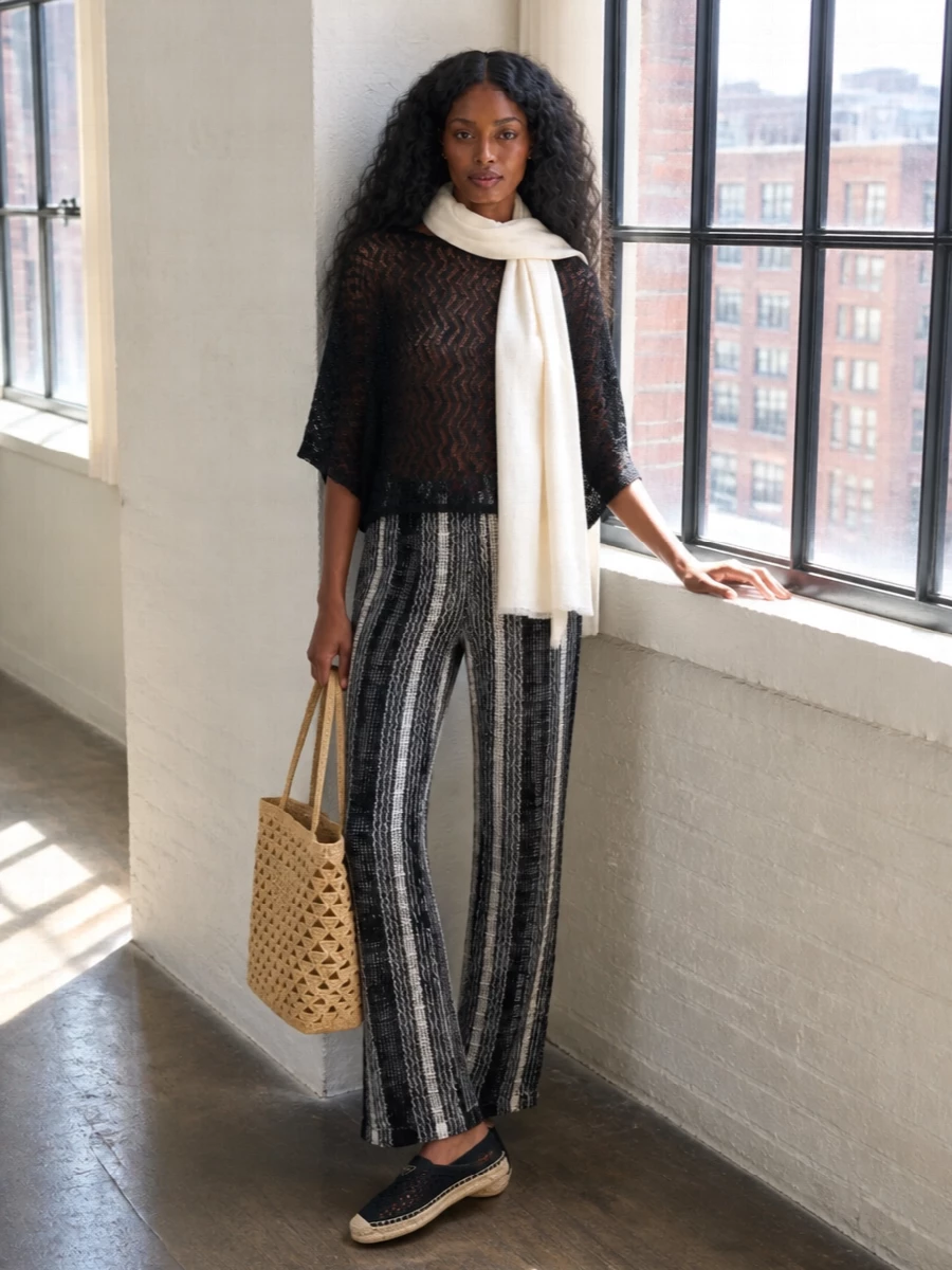 Monochrome Missoni textures keep this beach set quietly graphic, with black and cream zigzags and mesh playing off each other instead of competing for attention. Flat black espadrilles and a natural raffia tote ground the knit trousers in an easy, Riviera rhythm, while a gauzy ivory scarf softens the neckline for sundowners. It is relaxed, tactile and modern, perfect over swim or a simple black bikini top for long days that drift into evening.