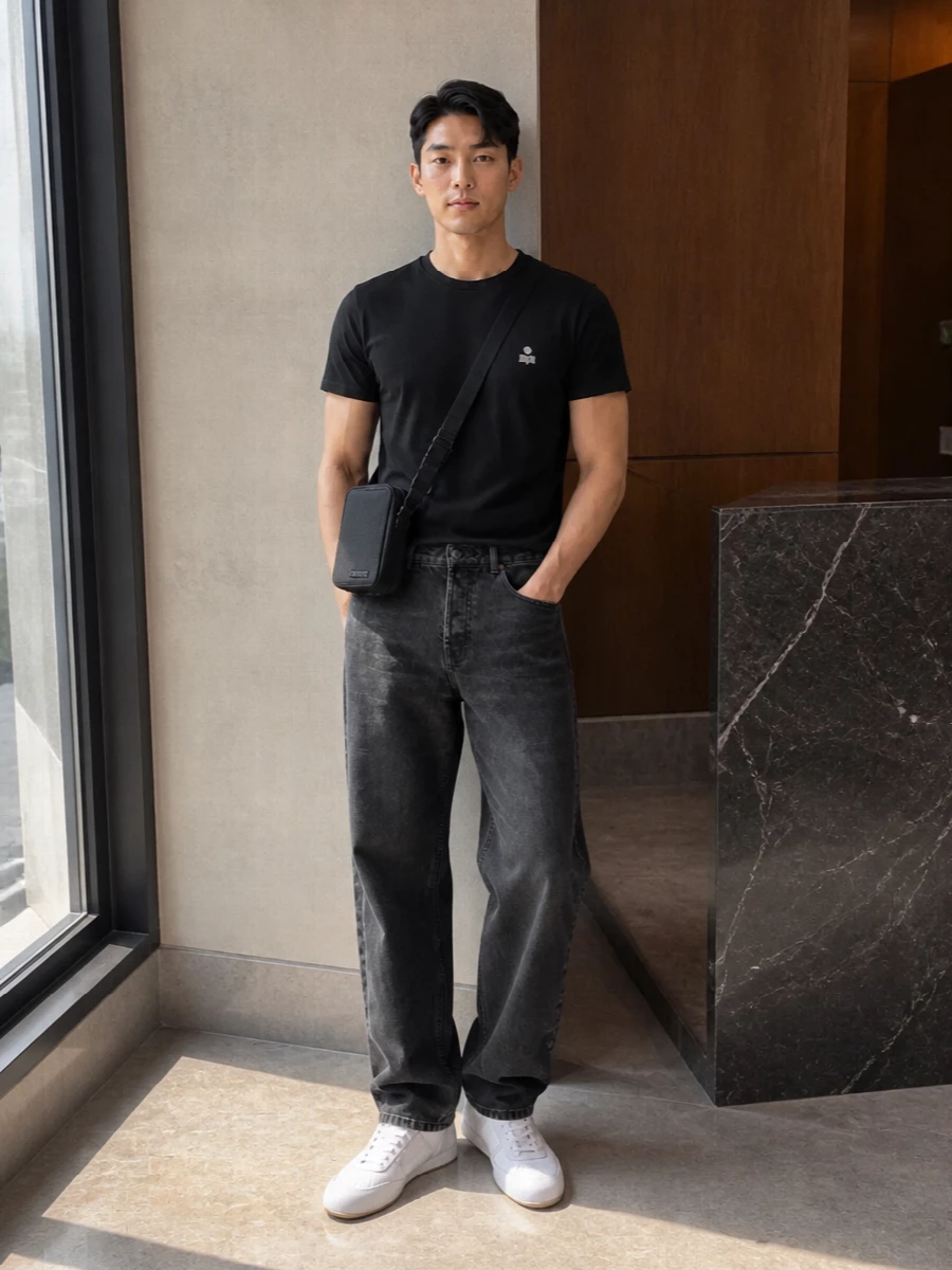 Ground the Isabel Marant tee with washed black straight denim for a quiet, monochrome base that feels relaxed but considered. Soft white minimal sneakers break the black just enough, while a slim Jacquemus crossbody and neat black socks keep everything sharp and city-ready without shouting about it.