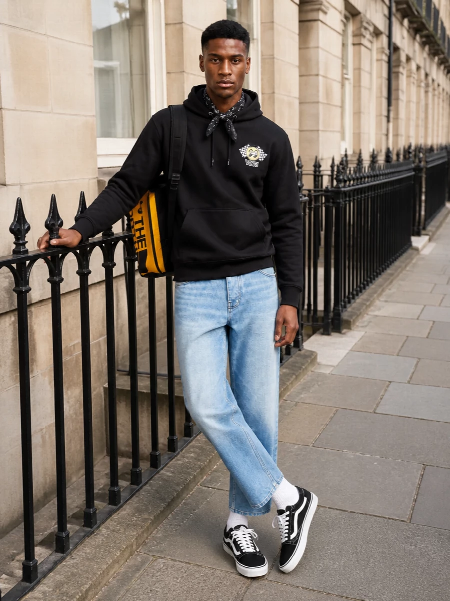 A city-ready skate uniform built around black Vans and light, cropped denim. The relaxed jeans keep the graphic hoodie casual and easy, while classic black-and-white sneakers and a tonal bandana sharpen the streetwear edge. Yellow accents from the backpack quietly echo the chest graphic for a pulled-together, all-day setup.