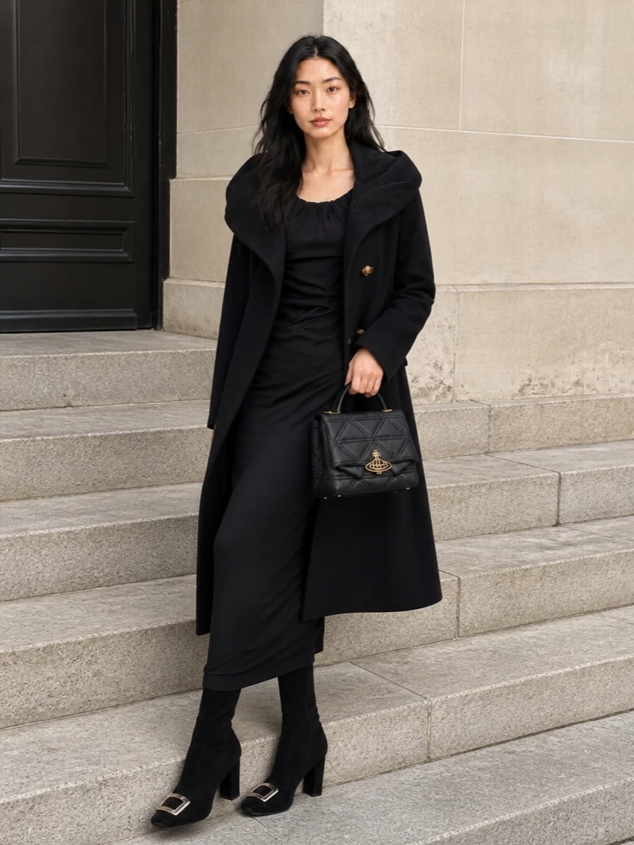 I’m styling this around the dress path so the coat can frame one continuous, sculpted black column rather than breaking it with visible tailoring seams. The ruched maxi and knee-high boots keep the silhouette long and dramatic, while the quilted top-handle bag adds a precise hint of shine that speaks to the coat’s gold buttons. It is a quiet yet theatrical evening ensemble for winter dinners and gallery nights where texture and line do all the work.