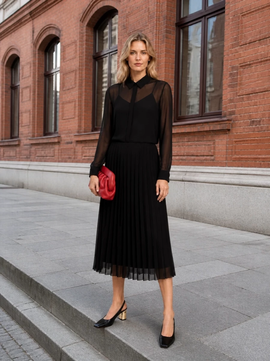 The Ami Paris black pleated shirt dress creates a clean, fluid canvas that highlights the sculpted cherry-red clutch rather than competing with it. I chose the dress path over separates to keep the silhouette long, uninterrupted and quietly formal, which best suits the bag’s gallery-opening-to-dinner energy. Grounded with the Givenchy black slingbacks, the result is a minimalist, evening-ready composition where colour and structure feel deliberate rather than busy.
