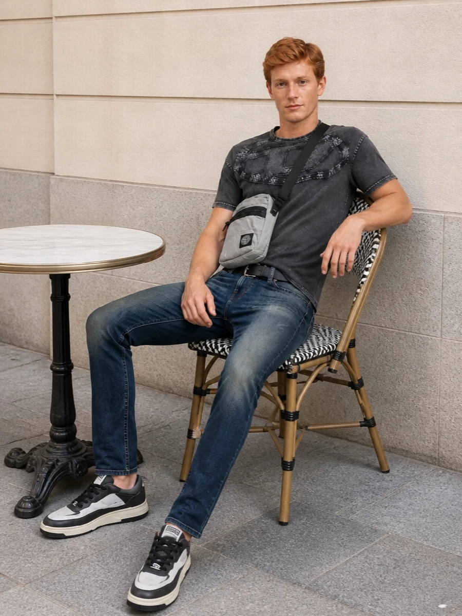 Faded slim Diesel denim meets a washed charcoal graphic tee for a street-led take that feels tough but easy. Charcoal and white sneakers keep the line clean while still reading urban. A compact grey technical crossbody and a minimal black belt finish the outfit with quiet utility rather than loud branding.