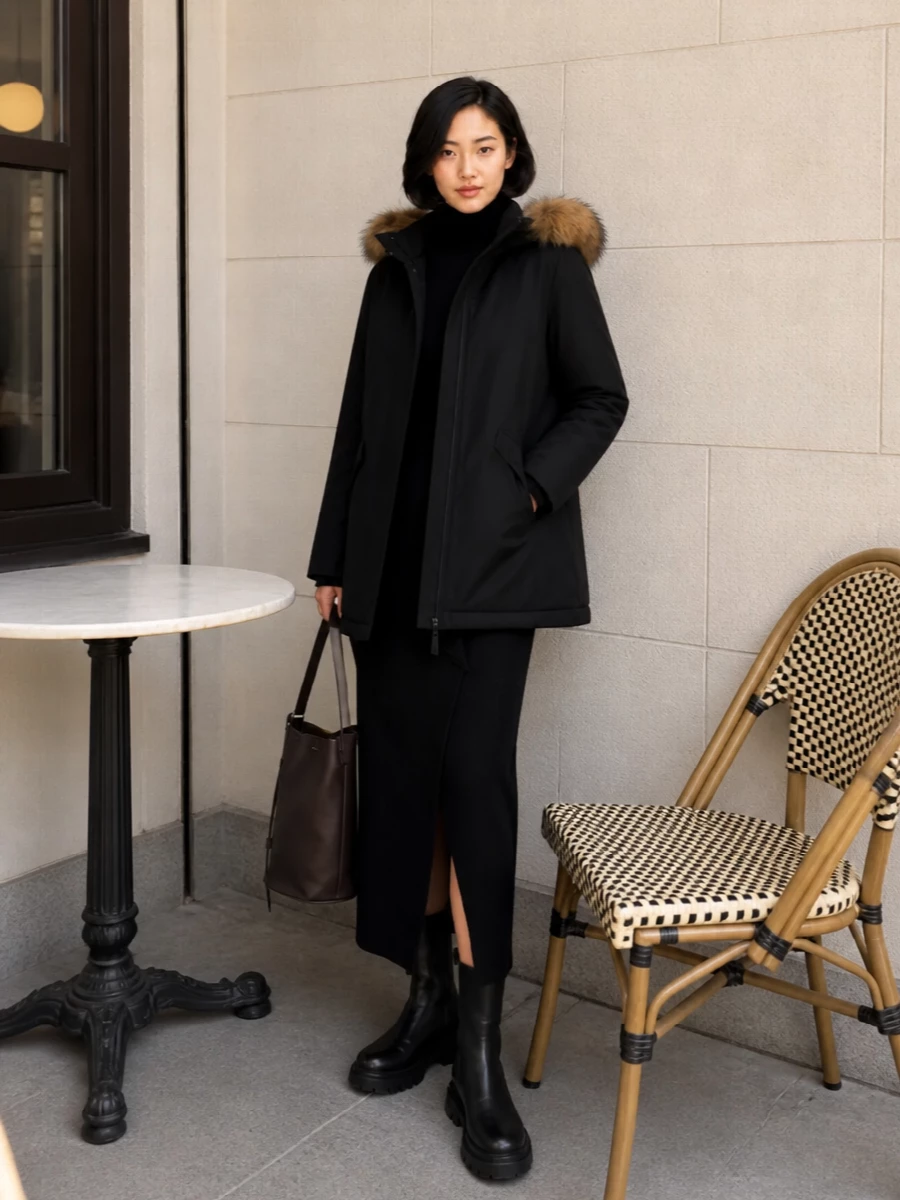 I’m anchoring this around the knit dress rather than separates so the parka sits over a single long column, which reads more intentional and polished with this level of minimalism. The black turtleneck midi and tonal chunky boots extend the clean, urban line of the coat, while the chocolate bucket bag picks up the warmth of the hood’s fur without breaking the monochrome mood. It feels like a quietly confident winter city uniform that moves from day to dinner with just a change of tights or jewelry.
