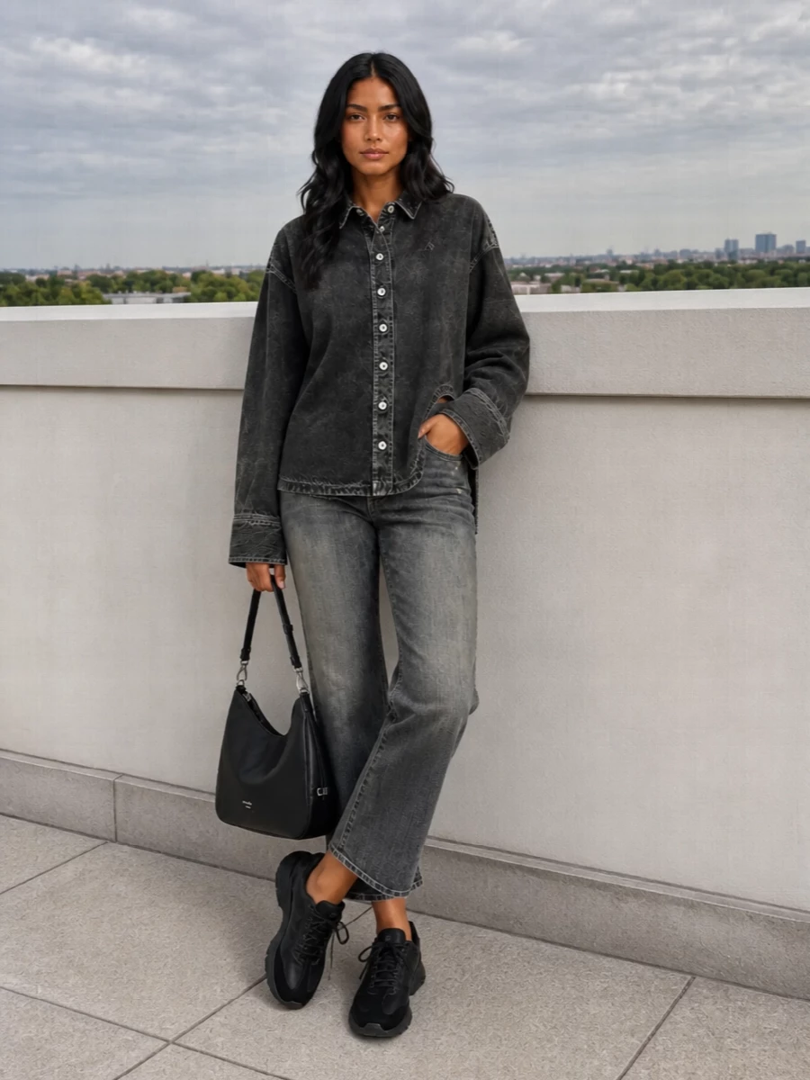 Washed charcoal on charcoal keeps this Balenciaga denim and Attico shirt pairing moody and precise, with distressing and asymmetric hems doing the talking. Grounded in black sneakers and a clean Prada shoulder bag, it reads like downtown streetwear that is considered rather than loud. The cropped jean and relaxed shirt proportions feel easy but intentional, perfect for city days that run late.