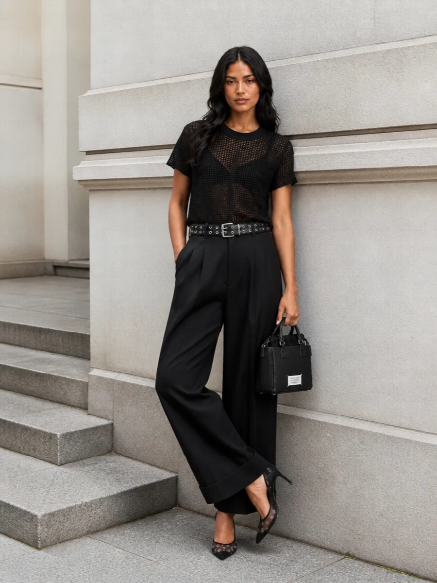 A sheer grid tee meets precise wide-leg tailoring for a monochrome silhouette that is clean, graphic and nightlife ready. Mesh stilettos and a grommeted belt pull the line into something deliberately sharp, while the compact box bag keeps the proportions close to the body and modern.