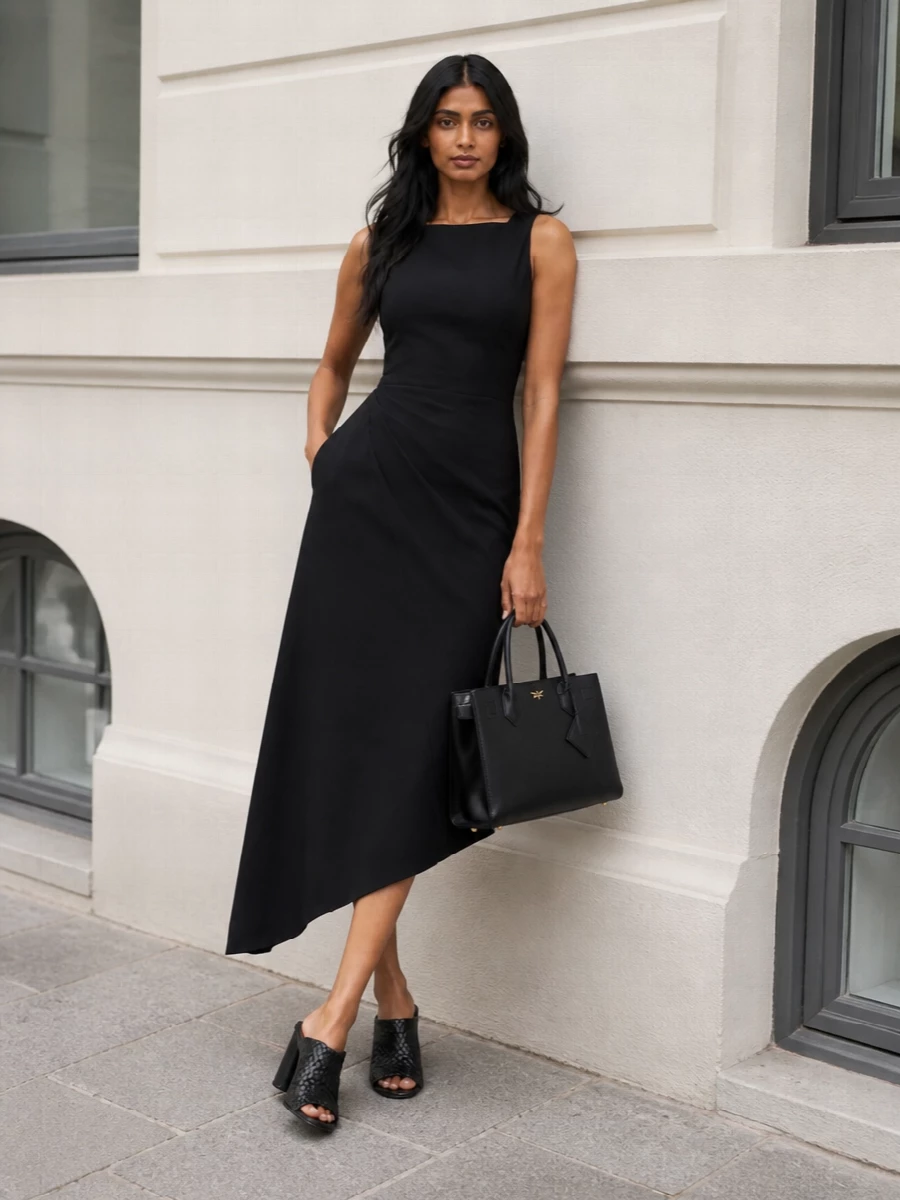 A sharply cut black midi dress and sculptural heeled mules frame the MCM tote as the quiet anchor, keeping everything in a single, confident palette. The asymmetric hem and woven leather texture add just enough movement and interest while still reading as boardroom-appropriate. Choosing the dress route over separates keeps the silhouette clean and uninterrupted, ideal when you want the bag and cut to speak more than the styling details.