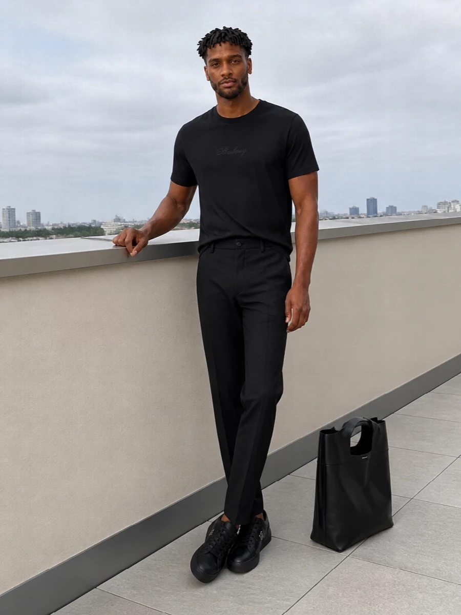 A deep black Burberry tee is anchored by Margiela’s high-rise tailored trouser for a monochrome line that feels precise yet relaxed. Fendi’s sleek black sneakers keep it city ready without tipping into formality, while the sculpted McQueen tote adds just enough structure for work, dinner or anything in between. The result is quiet luxury that reads considered from every angle but never tries too hard.