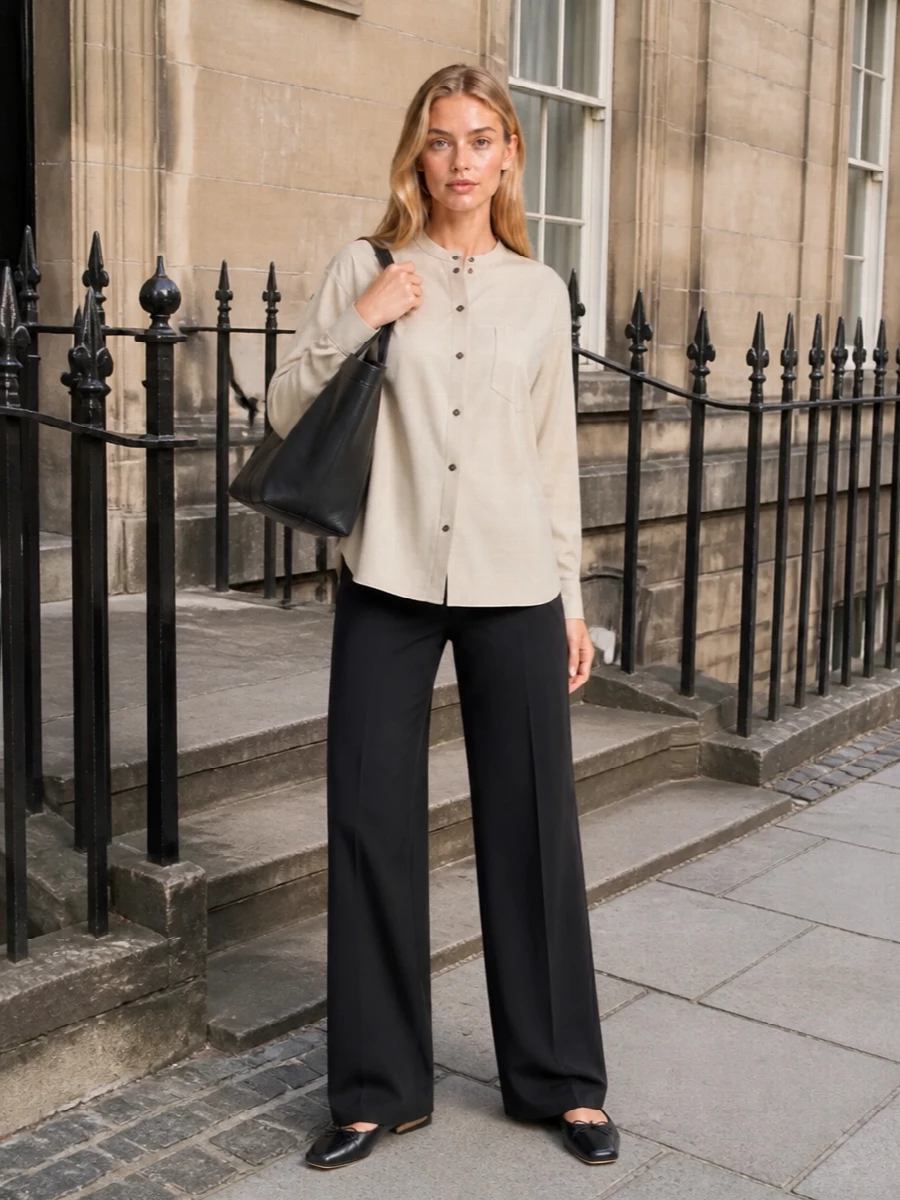 This is a quiet, office-to-dinner uniform built around sharp black tailoring and soft sand neutrals. The collarless shirt relaxes the structure of the long black trouser, while the architectural flats and structured tote keep everything minimal and precise. Choosing the top and trouser route, rather than a dress, keeps the look more versatile and aligned with the bag’s elevated everyday character.