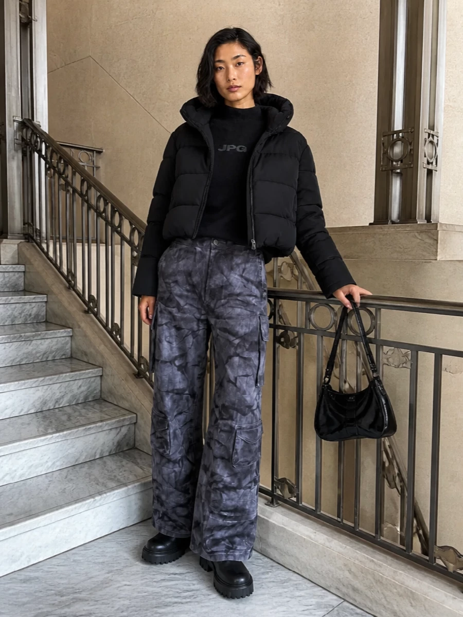 I am building around the outerwear with a top and bottom rather than a dress, because the cropped puffer wants that slouchy cargo volume and layered streetwear energy. The JPG knit, tie-dye cargos, and Hogan combats create a monochrome, winter-ready city uniform that feels directional but easy to wear. Diesel’s sculpted patent bag finishes it with a concise, nightlife-friendly hit of shine that still reads utilitarian and grounded.