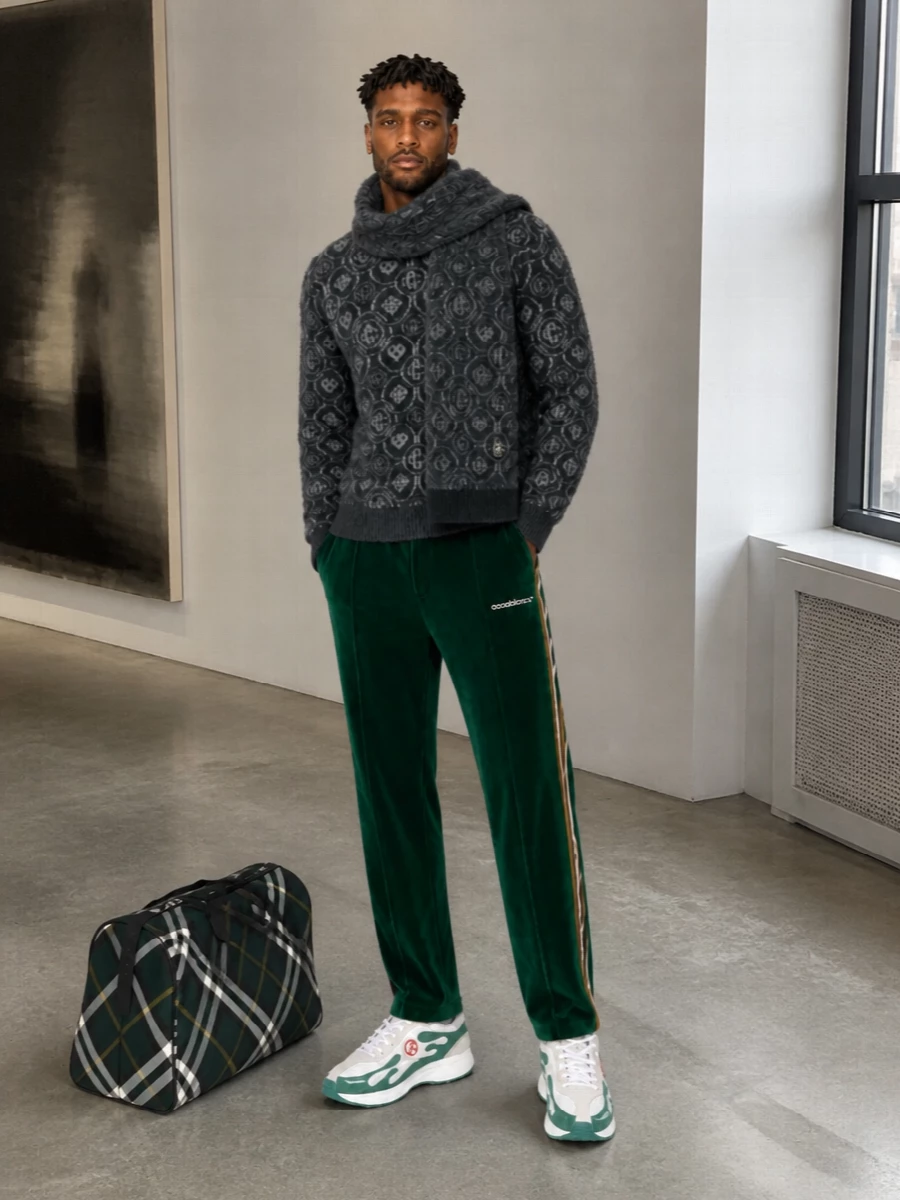 Deep greens and charcoals push this into a rich, winter-sport register that still reads considered rather than couch-bound. The fuzzy monogram knit and velour track pant play with texture while staying tonally precise, grounded by crisp white-and-green runners. A structured forest duffle and matching monogram scarf bring a quietly graphic finish that keeps the whole outfit firmly in the street-preppy, quiet luxury space.