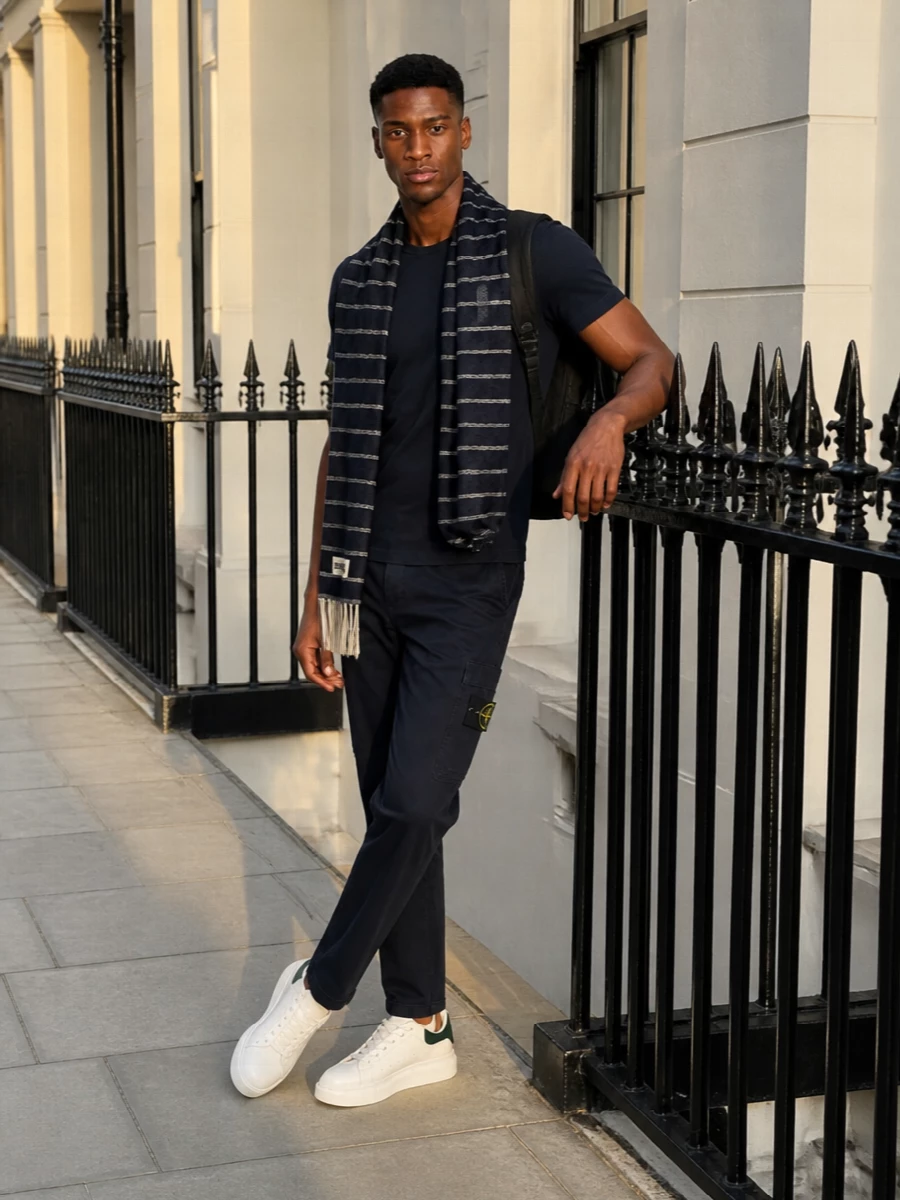 Deep navy on navy sets a calm, utilitarian base, with the cargo trouser echoing the tee’s clean lines but adding just enough pocket detail for interest. Crisp white and green sneakers keep the energy modern and light, while the technical backpack and striped scarf underline the city-ready, functional attitude without cluttering the silhouette.