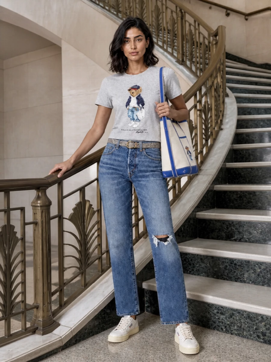 A heather-grey Polo Bear tee pairs with mid blue straight-leg denim for a clean, collegiate spin on casual days. Retro-style off-white sneakers keep it sporty but restrained, while the matching Bear tote leans into the playful prep. A slim neutral belt quietly sharpens the waist so the proportions stay easy but intentional.
