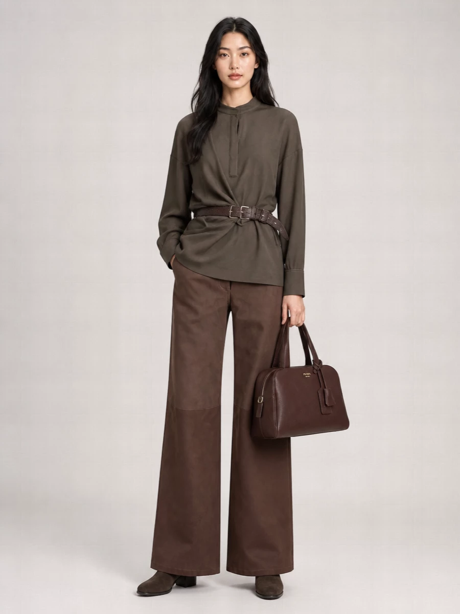 Rich chocolate tones run head to toe, with the belted blouse defining the waist against the easy, wide-leg trouser for a clean, elongated line. Dark suede ankle boots and a structured top-handle bag keep the mood quietly polished, while the textured belt brings just enough detail to break up the monochrome without disturbing the calm. It is a composed, city-ready ensemble that moves easily from daytime meetings to low-key dinner plans.