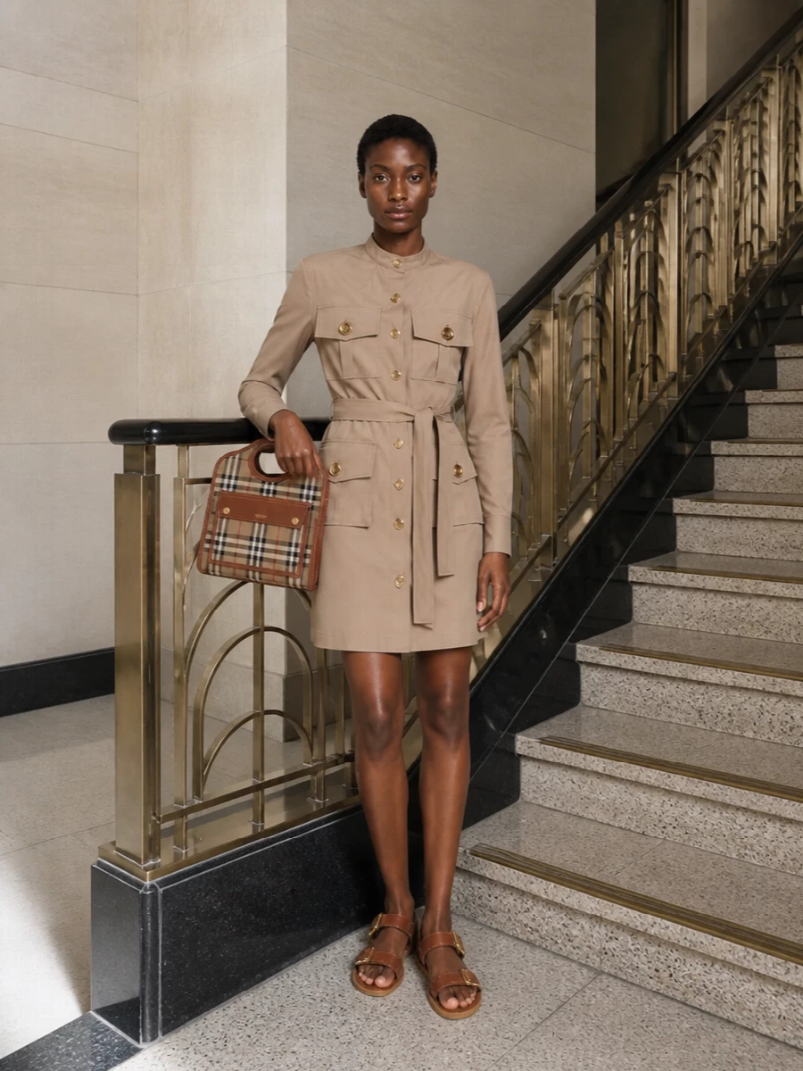 Anchoring the Burberry crossbody with the Givenchy taupe utility shirt dress keeps the story clean, tailored and quietly uniform, with warm neutrals echoing the bag’s camel check. The Valentino tan slingbacks introduce a subtle gold glint that talks to the bag’s hardware while staying low to the ground, so the whole outfit reads polished enough for meetings but relaxed enough for city walking. Choosing the dress route over separates lets the bag remain the focal check, supported by crisp, structured lines rather than competing patterns.