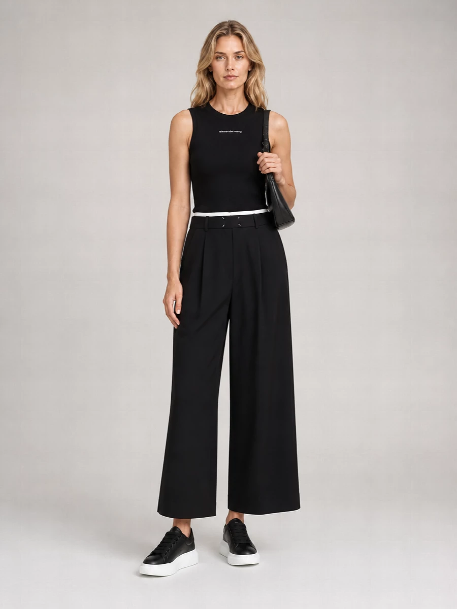 A sharp black Alexander Wang tank meets high-rise cropped wide-leg trousers for a clean monochrome base that feels polished but still easy. The sculptural McQueen sneakers ground the volume with a graphic sole, while the slim crescent shoulder bag and Margiela belt keep the lines tight and intentional. It is a quietly confident streetwear uniform you can wear from coffee runs straight into low-key dinners.