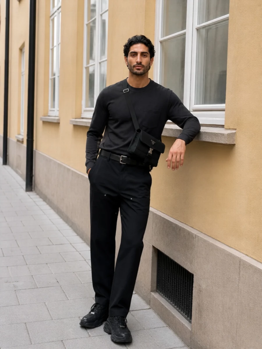 Technical tailoring stays relaxed with the Sacai trouser paired to the navy and taupe long sleeve, giving a clean block of structure through the upper body. Chunky black Balenciaga sneakers ground everything with a graphic, athletic edge, while the Prada crossbody and belt add just enough hardware to keep the monochrome streetwear polished rather than stark. It is a city-ready mix of utility and refinement that moves easily from daytime errands to low-key evenings out.