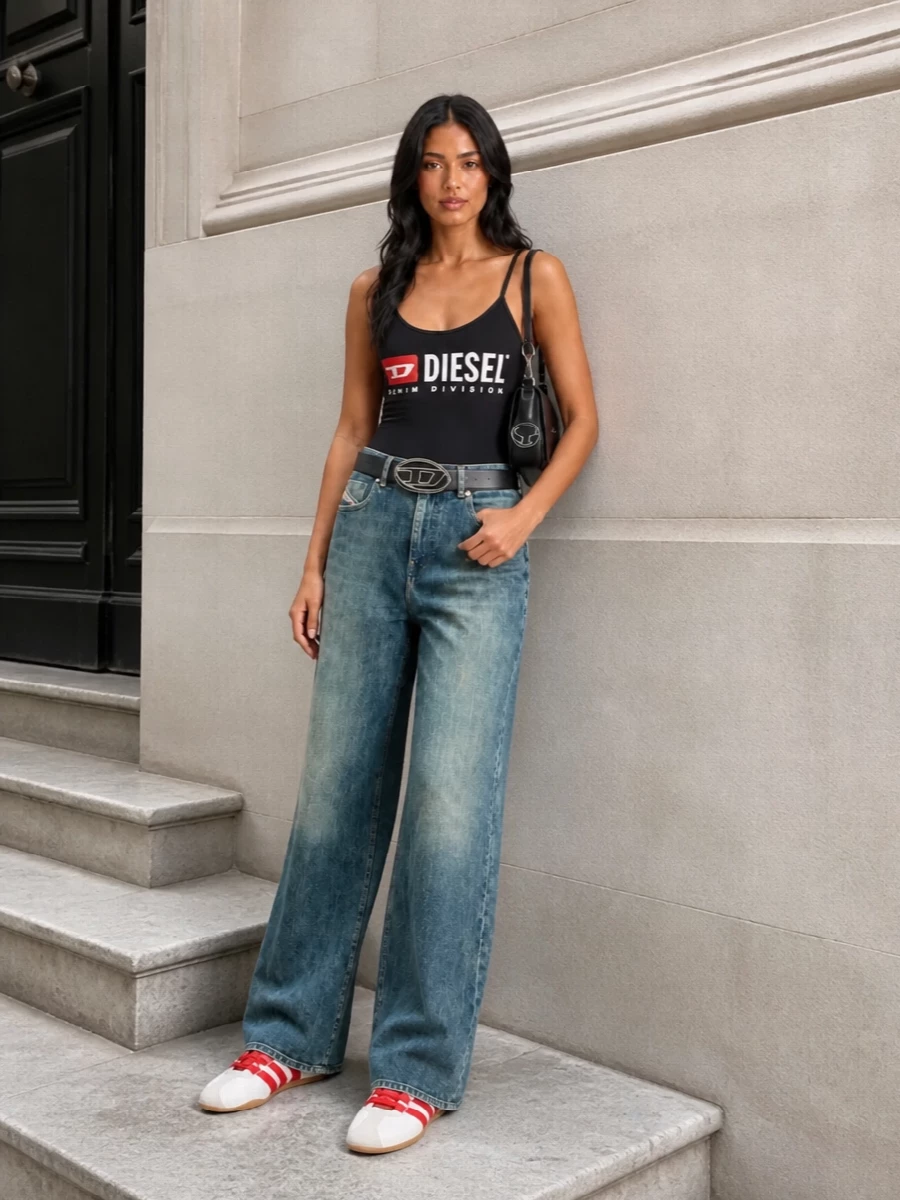 A graphic Diesel bodysuit meets high-waisted faded wide-leg denim for a clean, nostalgic streetwear take with real attitude. Low-profile red and white sneakers pick up the logo hits in a subtle way, while a structured black mini bag and bold belt buckle sharpen the whole outfit for city days that can easily run late.