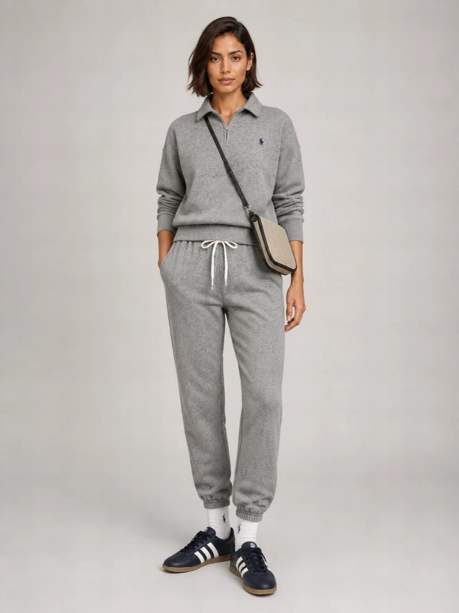 A heather grey quarter zip with matching joggers creates a clean, tonal base that feels relaxed but still considered. Navy terrace sneakers ground the set with a collegiate edge, while the beige canvas cross-body keeps the palette airy and practical. White ribbed socks with a navy logo quietly tie the sport and preppy elements together for easy weekend wear or travel days.