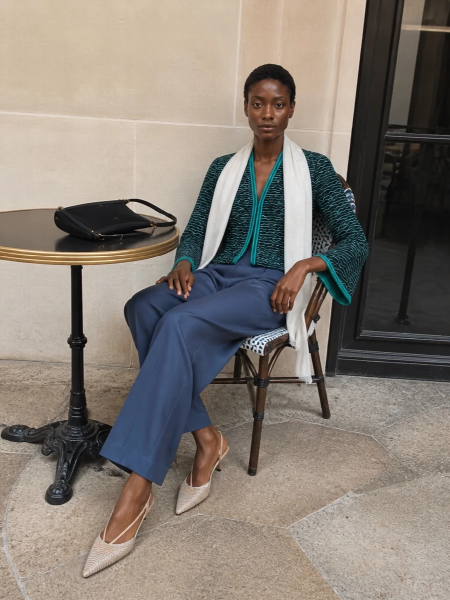 Deep navy tailoring and wave-textured jacquard create a long, polished column that feels modern for cocktails or dinner. The slate-navy trouser grounds the sculpted blouse, while nude slingbacks and a slim black shoulder bag keep the focus on clean lines and texture. A sheer neutral stole softens the edge just enough for warm evenings without diluting the quiet luxury mood.