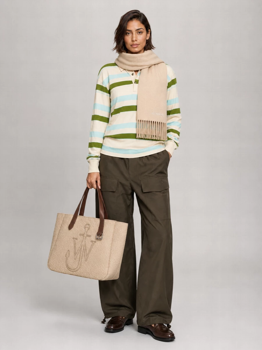 JW Anderson’s striped polo sits over the slouchy olive cargos for a relaxed, collegiate take on streetwear that feels playful but put together. Dark-brown loafers sharpen the volume of the wide leg while staying easy, and the oversized beige tote plus soft oatmeal scarf keep the palette warm and grounded for city days. It is a pulled-together weekend outfit that moves comfortably from coffee runs to casual dinners without losing that graphic knit as the hero.