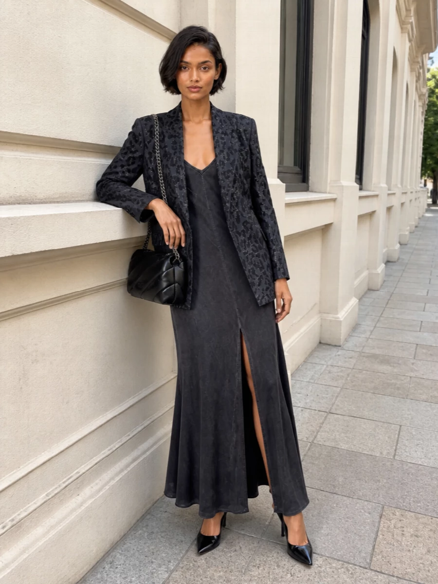 I am styling the sequinned leopard blazer over a charcoal slip dress rather than suiting separates, so the jacket stays the statement and the base reads fluid and sensual. Black patent pumps and a padded black shoulder bag in silver hardware keep everything polished and tonal, letting the animal jacquard and shimmer do the talking while still feeling sharply tailored for night.