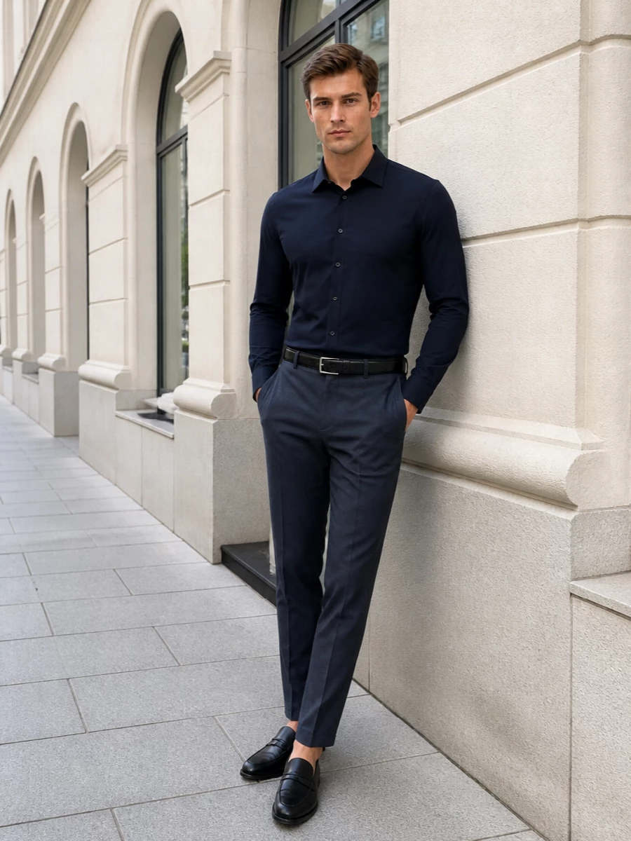 Charcoal-navy trousers and the clean navy shirt create a single, elongated line that feels calm, precise and unfussy. Black loafers and a woven black portfolio sharpen the mood without breaking the palette, keeping the whole outfit ready for long city days that slide into dinner. A discreet black belt finishes everything with just enough structure at the waist.