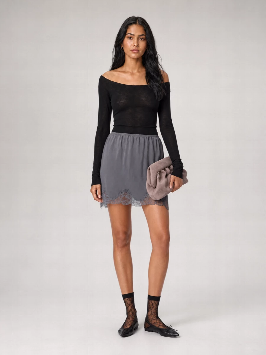 Charcoal lace, sheer black knit and mesh flats keep this set intimate and quietly sensual, perfect for evenings at home that might turn into a nearby dinner. The dusty mauve clutch and lace socks add a soft romantic note without breaking the monochrome calm, so it still feels relaxed, minimal and easy to live in. Wear the knit slightly off one shoulder to mirror the skirt’s scalloped movement and keep the proportions light on top, fluid on the thigh.