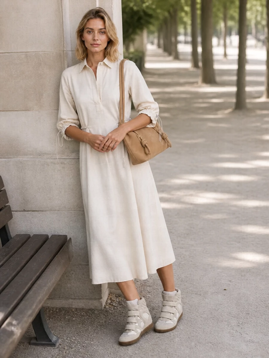Soft neutrals stay front and center with the ivory Max Mara shirt dress echoing the stone Isabel Marant wedges for a leggy, easy city uniform. The relaxed, belted shape keeps it unfussy yet considered, while the suede Hereu shoulder bag adds just enough warm contrast and texture to feel modern and street aware. Choosing the dress route lets the sneakers’ sculpted profile stay the focal point rather than fighting volumes with wide-leg tailoring.