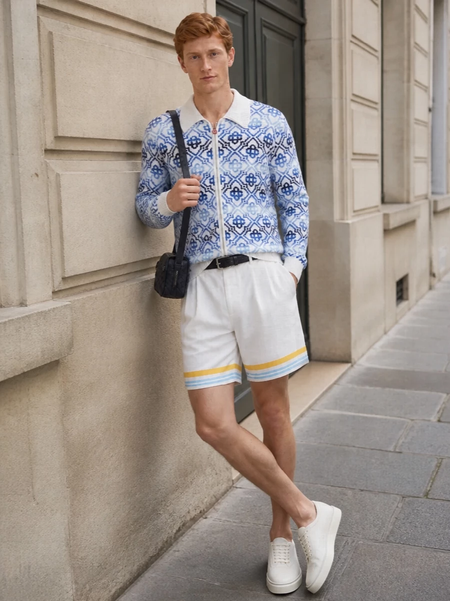 The look leans into Casablanca’s Riviera-preppy language: the geometric zip cardigan stays hero, grounded by refined white shorts that only echo its blue and yellow notes at the hem. Off-white luxury sneakers and a navy intrecciato crossbody keep the palette cool and minimal, so the knit reads plush and intentional rather than busy. A slim, discreet belt quietly structures the waist while preserving the easy, resort-ready attitude.