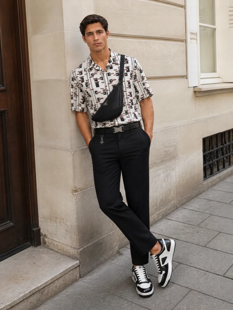 This look frames the graphic Prada shirt with inky black tailored trousers for a long, disciplined silhouette that keeps the print feeling sharp rather than casual. Black-and-white court sneakers echo the shirt’s contrast while staying luxe and city-ready, and a sculpted black crossbody plus a clean technical belt finish the outfit with quiet, architectural polish. It’s an SS ensemble that feels intellectual, modern and precise—ideal from gallery afternoons to sleek evening drinks.