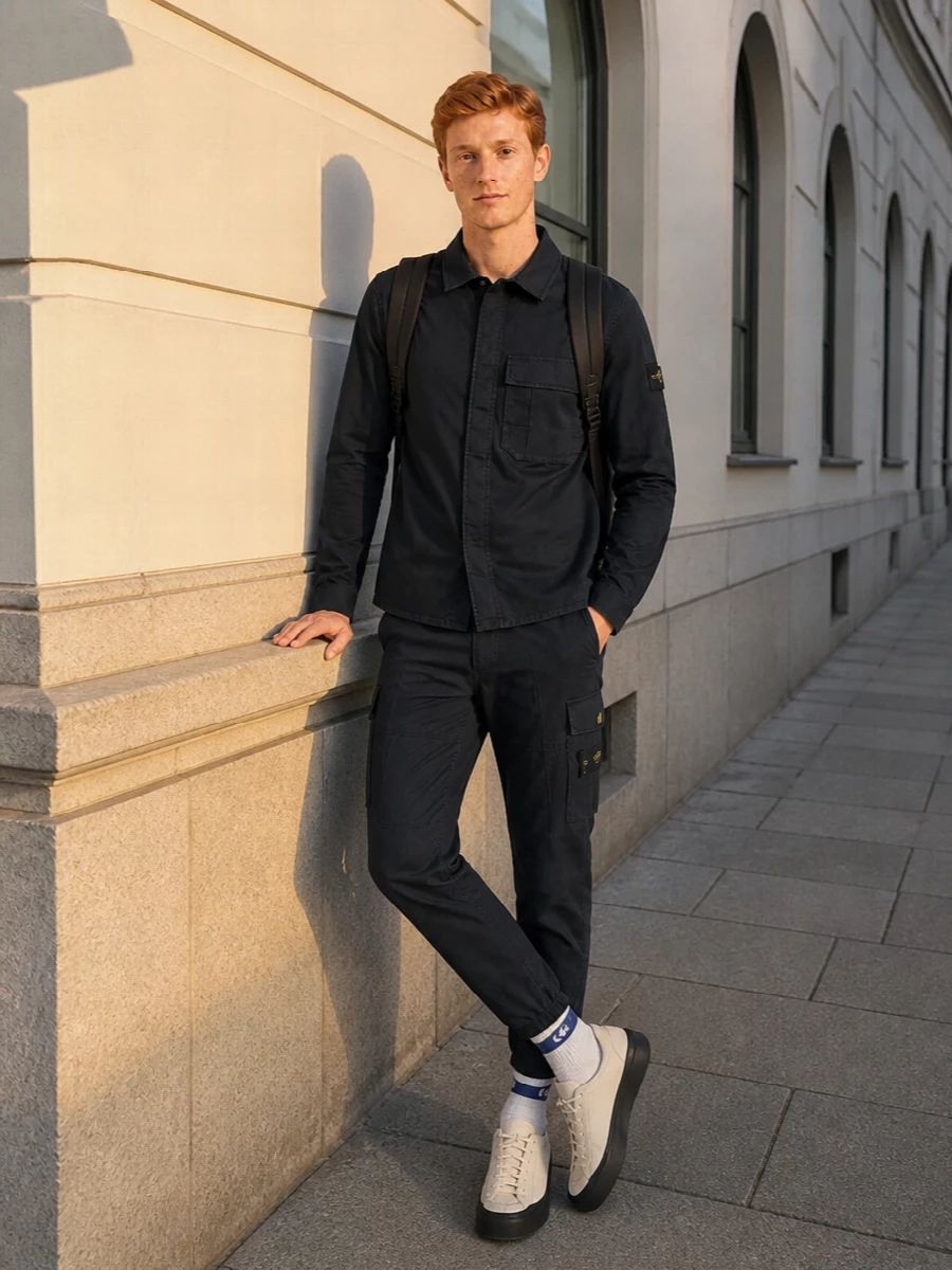 Deep navy cargos with the matching Stone Island shirt create a tight, technical street uniform that feels intentional rather than busy. The neutral runners and striped socks break the darkness just enough, keeping the palette muted while nodding to sport. A black backpack finishes it with functional structure that still reads clean and urban.