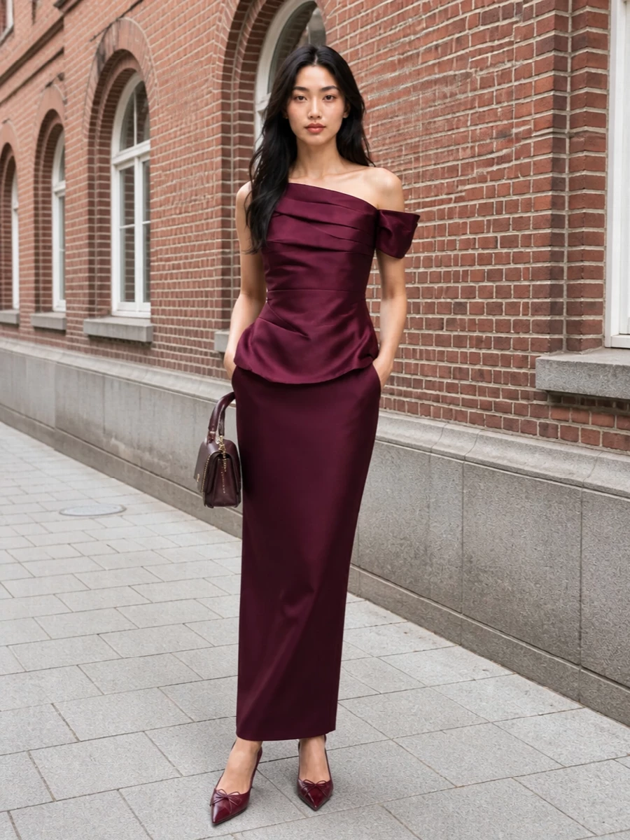 A deep wine column dress is grounded with tonal mesh pumps and a compact plum top‑handle, keeping the palette rich and restrained. The mix of satin and sheer textures reads quietly luxurious, ideal for intimate dinners or gallery evenings where the color does the talking.