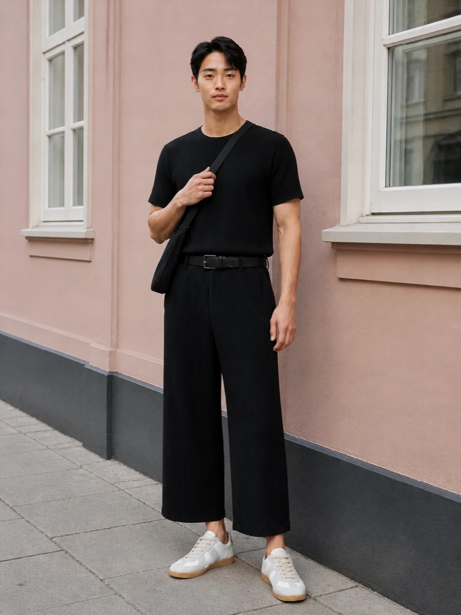 Monochrome pleats stay sharp and easy here: a black Homme Plissé tee skims into the cropped wide leg for a continuous, architectural line. Off‑white Margiela sneakers break the black just enough, keeping the mood relaxed and modern. A pleated crossbody and discreet Margiela belt echo the texture, so the whole outfit reads considered without feeling dressed up.
