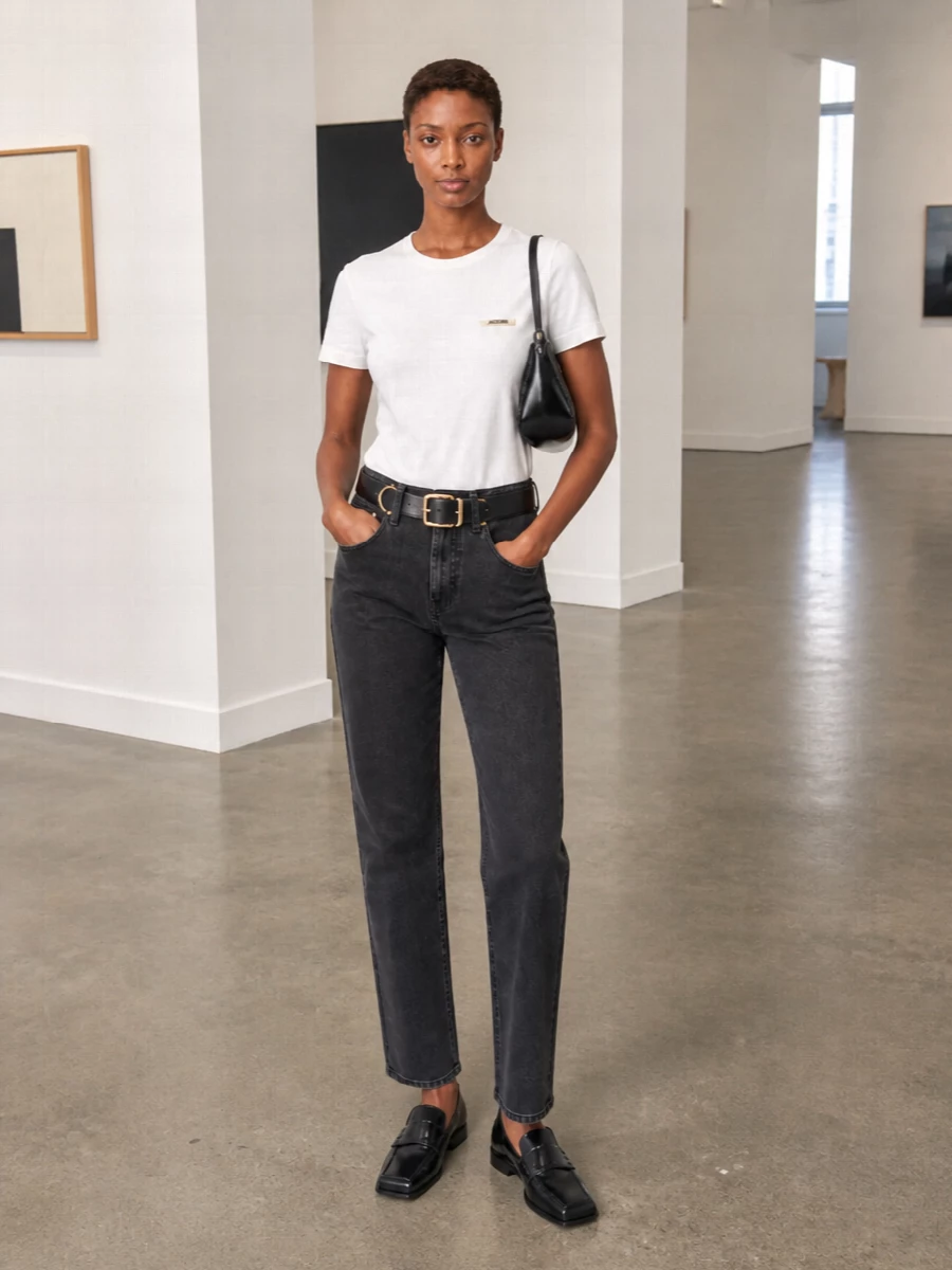 Crisp white Jacquemus cotton meets charcoal Totême denim for a clean, city-ready base with just enough structure. A square-toe Jacquemus loafer and glossy black baguette sharpen the palette while the gold-detailed belt quietly echoes the tee’s plaque. The result is a pared-back, quietly luxurious uniform that works from studio hours to late dinners without changing a piece.
