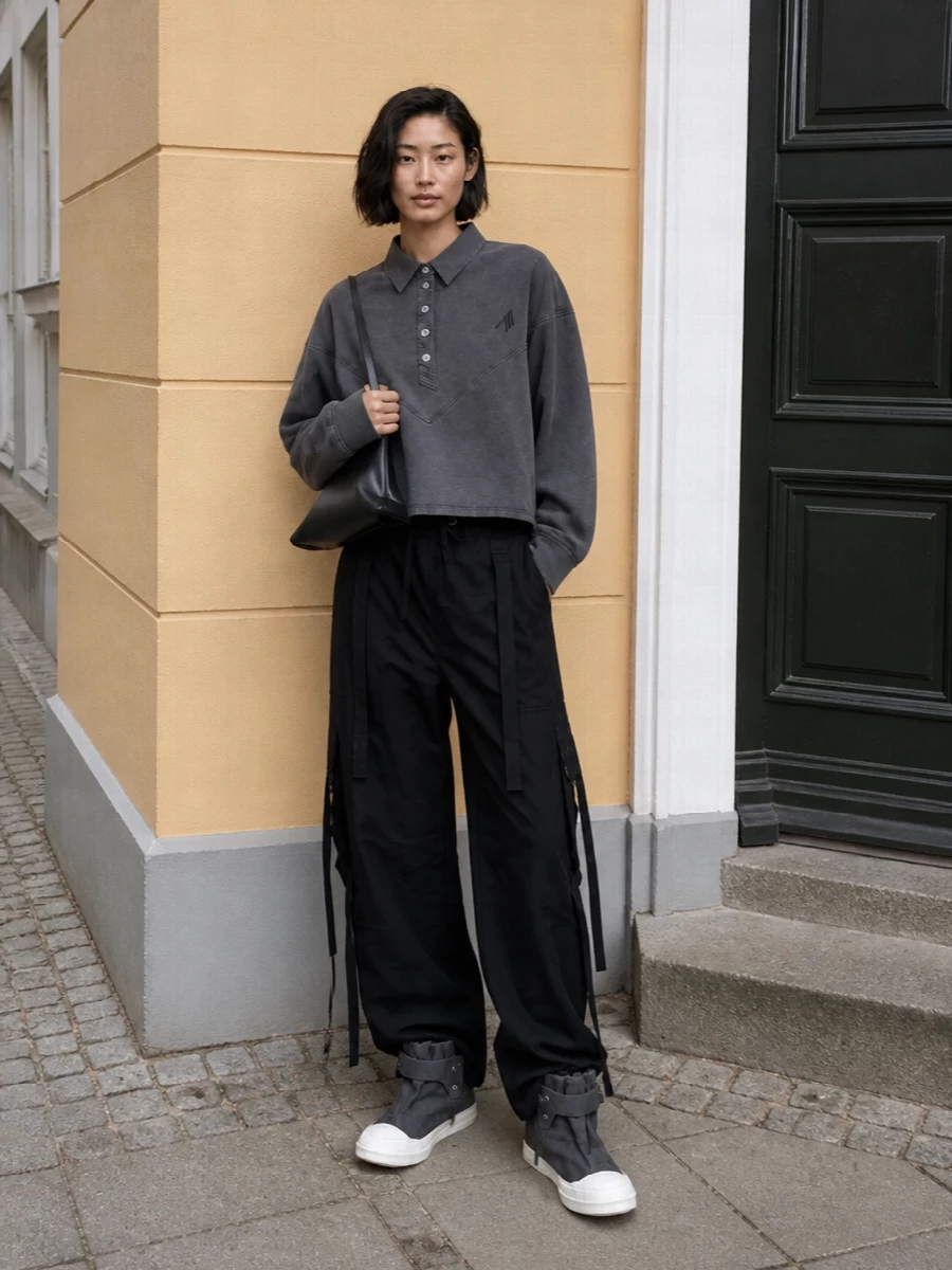 Dolce&Gabbana’s black cargos go full downtown with The Attico’s washed-charcoal pullover, keeping everything relaxed but deliberately sharp. Rick Owens DRKSHDW high-tops echo the graphic volume through the leg, while The Attico’s sculptural black bag brings a subtle, architectural edge that keeps the all-dark palette feeling intentional rather than heavy. It’s a cold-season city uniform with a quiet, directional attitude and a strong streetwear backbone.