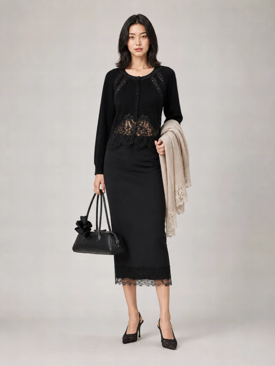 A monochrome column of lace-trimmed knit and pencil skirt keeps the silhouette long, lean, and quietly sensual. Black lace slingbacks sharpen the mood, while a sculptural shoulder bag adds just enough structure without breaking the softness.