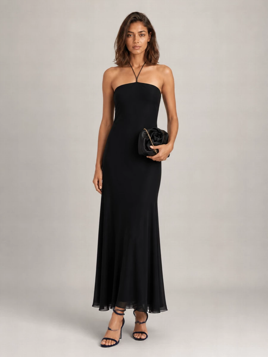 This is a sharply minimal evening column built around The Row’s halter dress, allowing the navy velvet spiral sandals to become a sculptural focal point. The liquid black silhouette, bare shoulders and micro-metallic accents read as quiet luxury rather than overt glamour, with the softly structured Burberry clutch adding just enough texture and shine for winter nights. I chose the dress route over separates to keep the line uninterrupted and let the shoe and accessories carry the drama without visual noise at the waist or hem.