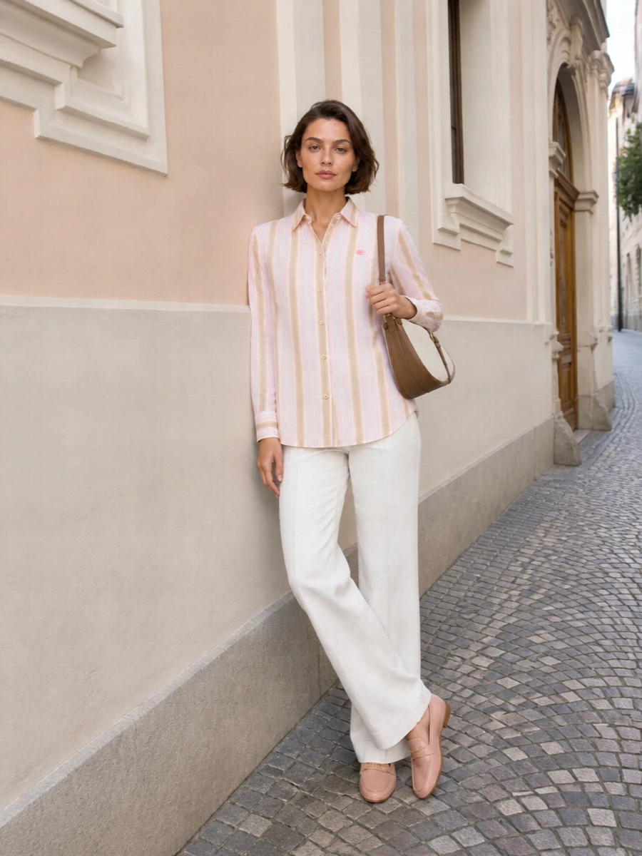 Soft stripes and ivory tailoring create a polished summer uniform that feels relaxed yet considered. The longline shirt skims neatly over the fluid wide leg, while blush leather and ecru canvas keep the accessories gentle and refined. It is an easy city-to-coast combination with subtle color harmony rather than overt print or hardware statements.