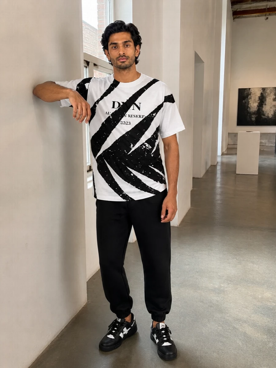 A monochrome street set built around sharp graphics, this pairing lets the Off-White sneakers, DVN tee and clean joggers speak the same black and white language. The proportions stay easy and athletic, with a boxy upper and tapered leg that feel skate-adjacent rather than sloppy. Prada’s streamlined crossbody keeps the whole thing luxe and functional for all-day city wear.